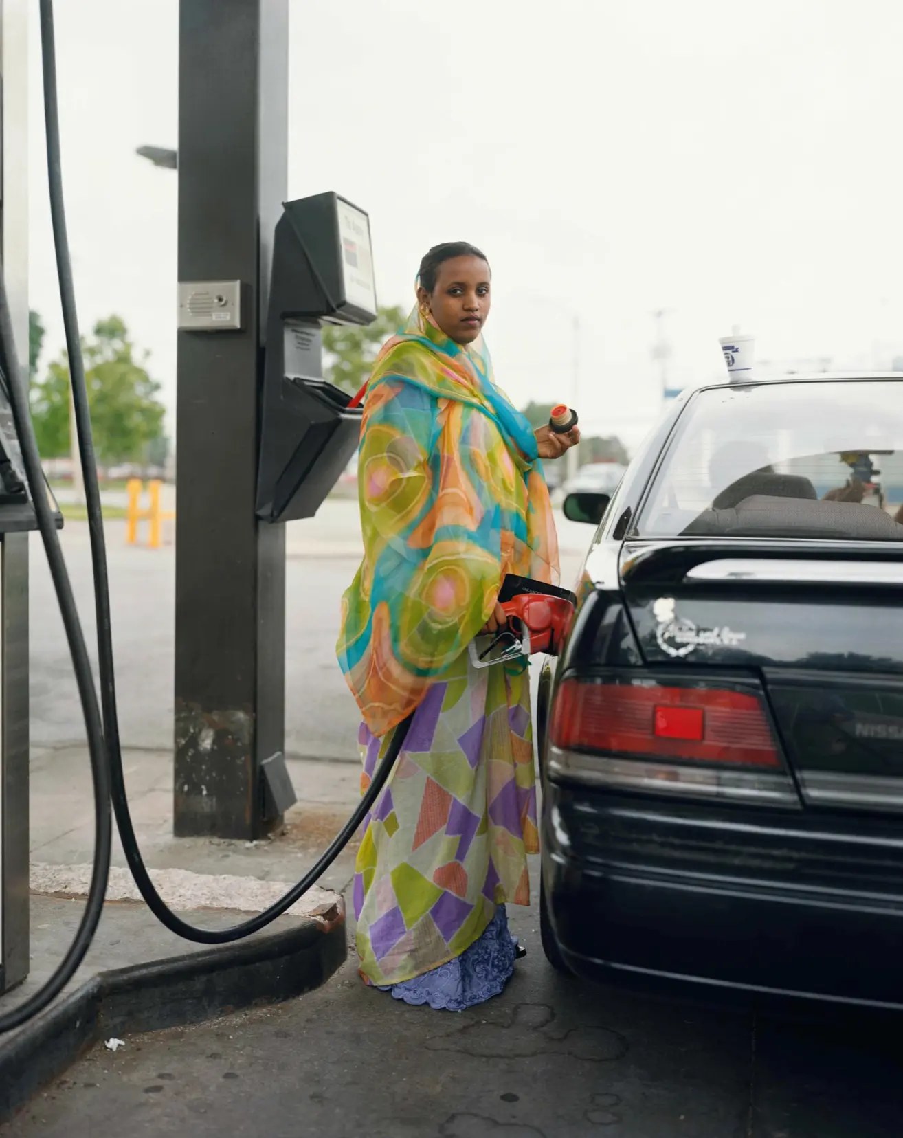 Joel Sternfeld, A woman Pumping Gasoline, Kansas City, Kansas, June 1999, 1999